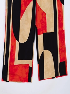 Detail of wide-leg trousers featuring abstract geometric print in red, black and beige
