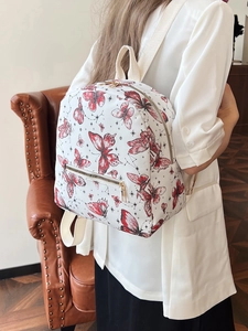 White backpack with butterfly print and gold zippers worn by model in vintage setting