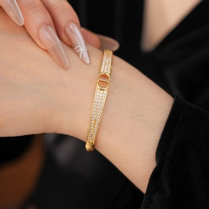 Detailed view of gold plated bangle with pavé crystals and CD letter emblem on wrist