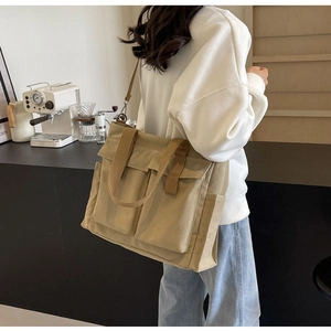 Macro shot of khaki canvas tote bag featuring double front flap pockets and adjustable strap