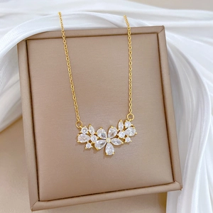 Macro view of gold flower necklace with clear zircons on white silk background