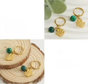 Détail de créoles plaquées or 18 carats avec perles de malachite et breloques Hamsa