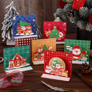 Close-up of assorted 3D pop-up Christmas cards with gold foil on a festive wooden surface
