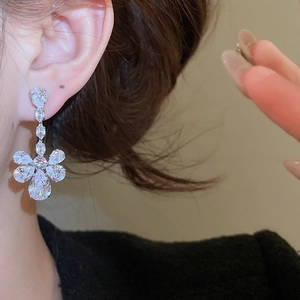 Close-up of elegant silver drop earring with marquise cut zircon worn by model