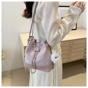 Detail view of pink bucket bag featuring chain strap and cute plush bear charm decoration
