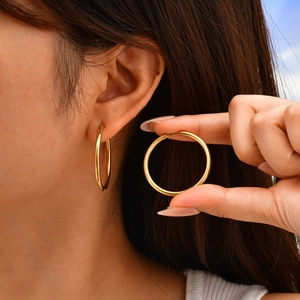 Polished gold stainless steel hoop earring shown on ear for realistic size perspective