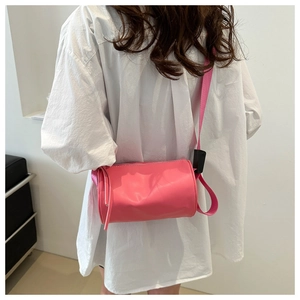 Borsa a tracolla cilindrica rosa mostrata su un modello in stile estivo casual