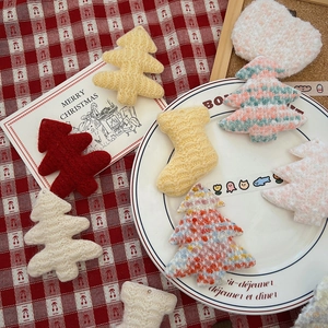 Detail of handmade knit Christmas tree ornaments on festive red and white plaid fabric