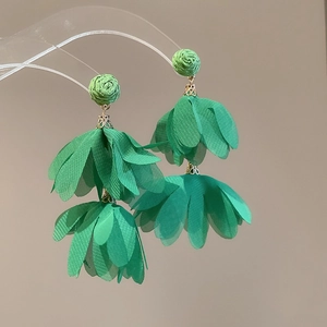 Close-up of green double-layer fabric flower earrings with woven stud on display stand