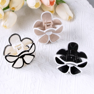 Drei minimalistische Blumen-Haarklammern in Creme, Khaki und Schwarz auf Strickstoff