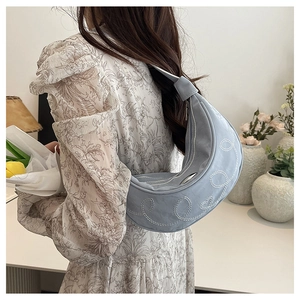 Borsa hobo celeste con ricamo a cuore indossata da modella in abito a fiori