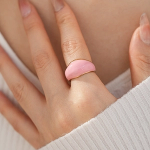 Close-up of pink enamel chunky dome ring worn by a model against white fabric