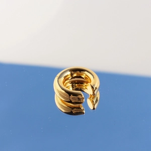 Minimalist 24k gold-plated C-shaped ear cuff with polished surface on blue mirror