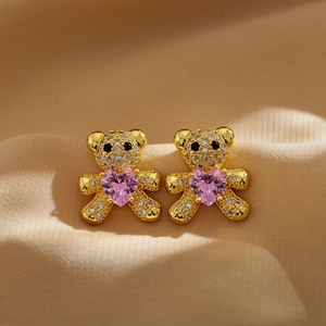 Micro-paved gold bear stud earrings with pink heart gemstone on silk background