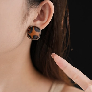 Gros plan sur des boucles d'oreilles carrées en similicuir à motif léopard sur un mannequin