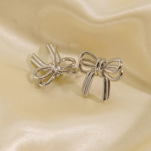 Polished silver bow knot stud earrings for women on elegant champagne silk fabric