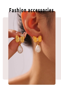 Detail of gold bow earrings with crystal accents and teardrop pearls on a model