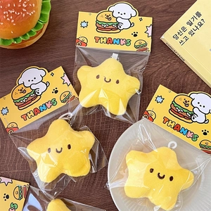 Detalle del llavero de estrella de peluche amarillo con cara sonriente en su empaque