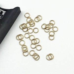 Scattered small golden open jump rings for DIY jewelry making on white background