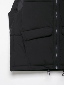 Close-up of black puffer vest with zipper closure, large pockets and drawstring hem