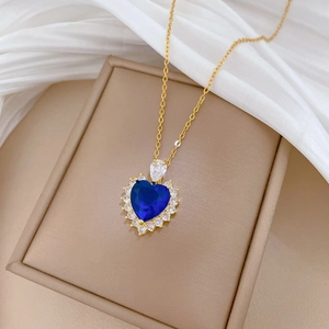 Close-up of heart-shaped blue sapphire pendant with diamond halo on golden chain