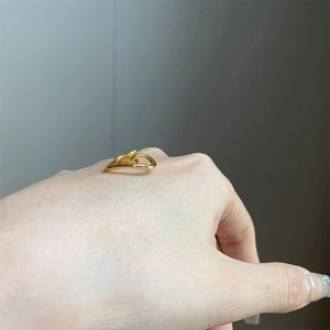 Detailed view of a gold wavy adjustable ring worn on hand, featuring a modern design