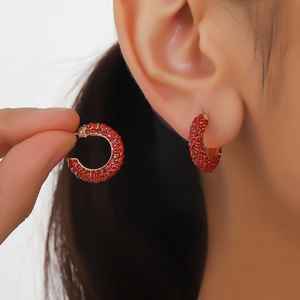 Close-up of model wearing geometric C-shaped red rhinestone hoop earrings in alloy