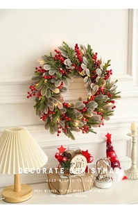 Detail of 40cm Christmas wreath with red berries and warm LED lights on a white wall