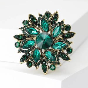 Vintage gold floral brooch featuring emerald crystals and multi-layer gemstone petals