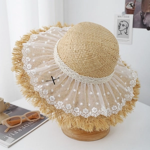 Détail d'un chapeau en paille avec broderie de dentelle blanche et élégant nœud noir