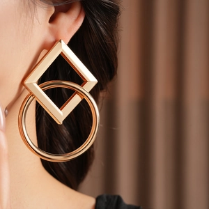 Gros plan de boucles d'oreilles dorées avec cercles géométriques creux et carrés