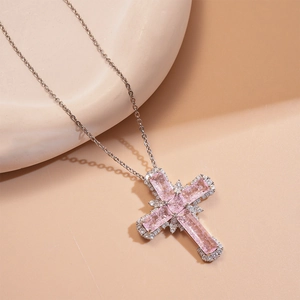 Vue détaillée du pendentif croix argenté avec pierres roses et bordure en cristal