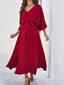 Detail view of the elegant burgundy V-neck dress featuring batwing sleeves and waist tie