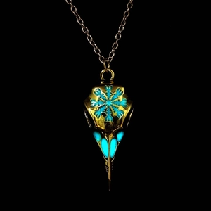Macro shot of luminous blue snowflake pattern on gold vintage raven skull pendant necklace