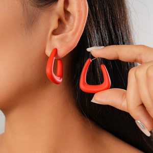 Close-up of a model wearing frosted red geometric C-shaped earrings with acrylic texture