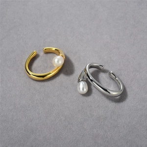 Detailed view of minimalist gold and silver ear cuffs with pearls on grey background