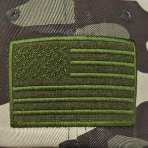 Macro detail of military camo cotton fabric and embroidered USA flag patch on baseball cap