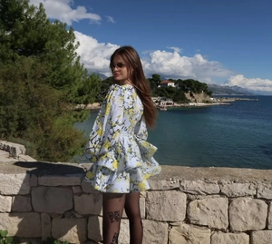 Detail of yellow floral dress featuring ruffled tiered hem and black printed stockings