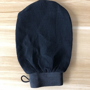Close-up of black exfoliating Moroccan bath mitt with textured sand surface and hanging loop