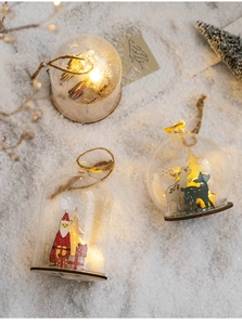 Detail of a Christmas glass globe night light with warm LED on faux snow background