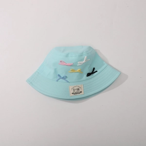 Detail of light blue sun hat with colorful bow accents and premium sewn fabric label