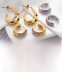 Detail of C-shaped and round hoop earrings with purple zircon in titanium steel