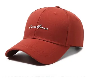 Detail view showing the side of a brick red baseball cap with white Constance embroidery