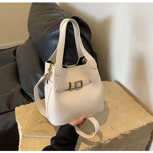 Detailed view of cream pebble leather bucket bag with gold hardware and dual straps