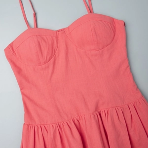 Detail of coral cotton sundress with slim straps and gathered waist texture