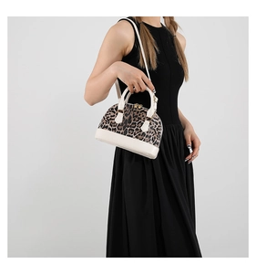 Leopard print shell bag with golden zipper and detachable strap shown on a model