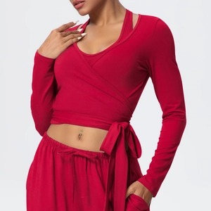 Detail of red cross-wrap long sleeve yoga top with waist tie and soft knit texture