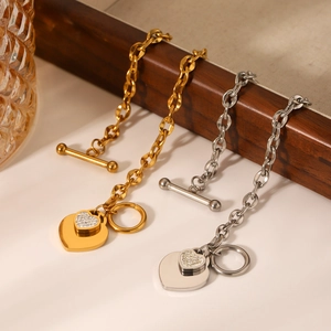 Gold and silver OT clasp chain bracelets with zircon heart pendants on a display stand