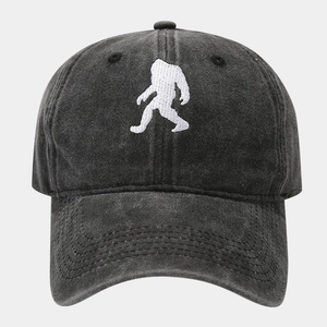 Close-up of embroidered white Bigfoot silhouette on vintage washed grey cotton baseball cap