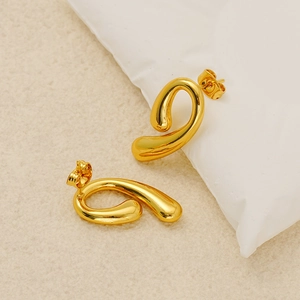 Macro shot of polished gold-plated comma-shaped earrings with reflective metallic finish